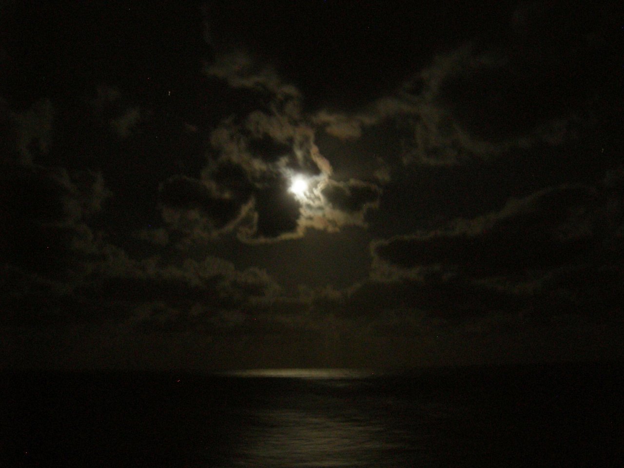 The moon was glowing through the clouds.
