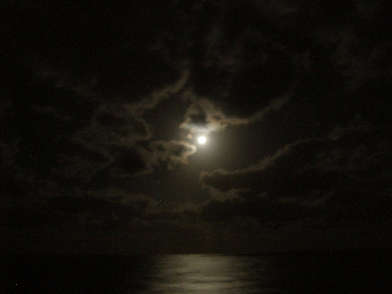 The moon was glowing through the clouds.